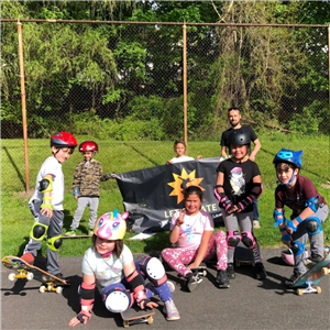 Kids pose with skateboards and let's skates sign