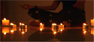 Candles in front of a person doing a seated yoga pose