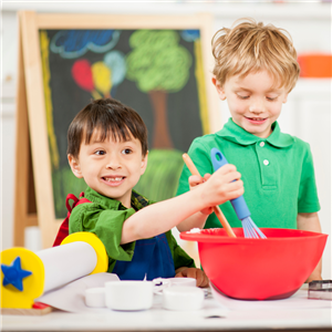 Two young boys using a whisk and spoon in a mixing bowl