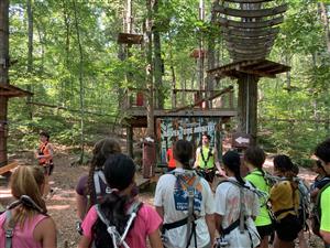 Campers listen to instructors at a ropes course