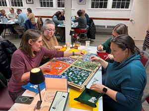 a 4 person team completes a puzzle at a table