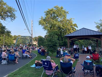 People sitting in lawn chairs watching the jazz alliance perform at the Flower Bridge